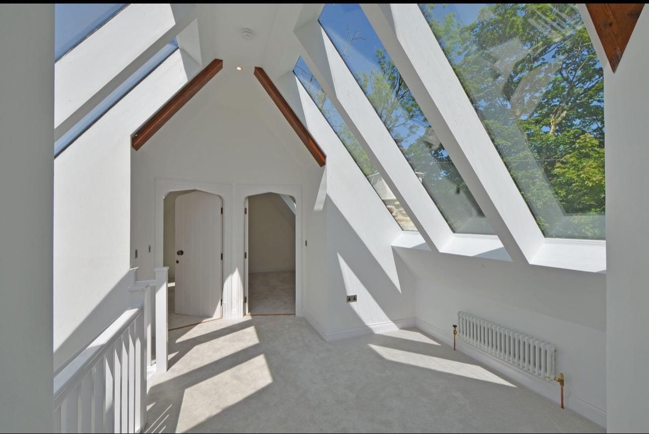 Finished vaulted room with glazed roof panels, exposed timber at the apex and two arched doors