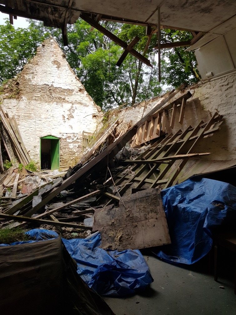 Collapsed roof timbers inside the stone walls before the restoration