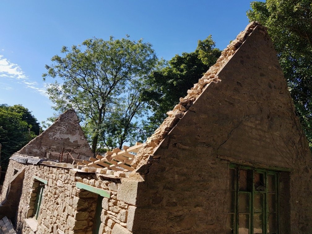 Roofless stone building with broken roof timbers along the wall tops
