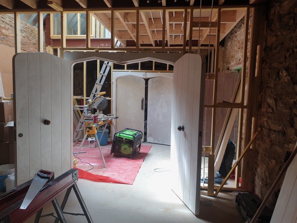 Arched timber door frames and plank doors fitted inside the stone walls during the build