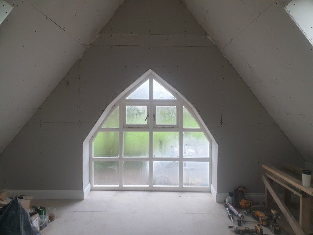 Plasterboarded room in the roof with a pointed arched window in the gable