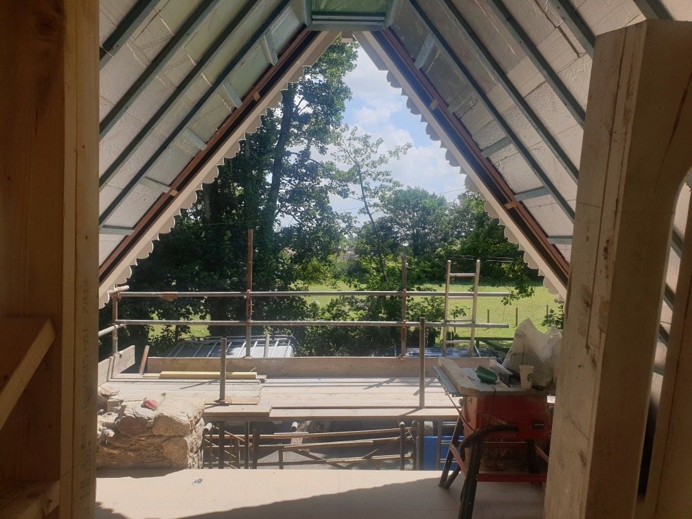 Open stone gable during the rebuild, with scaffolding and new roof timbers