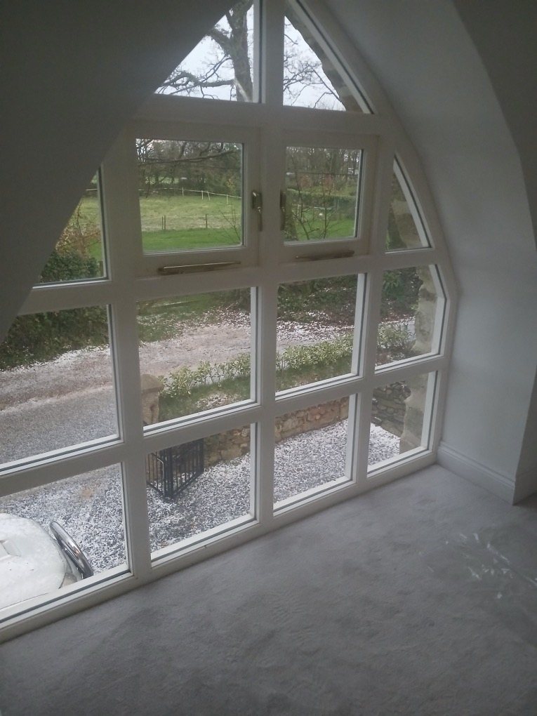 Large arched gable window seen from inside, looking out to the lane and fields