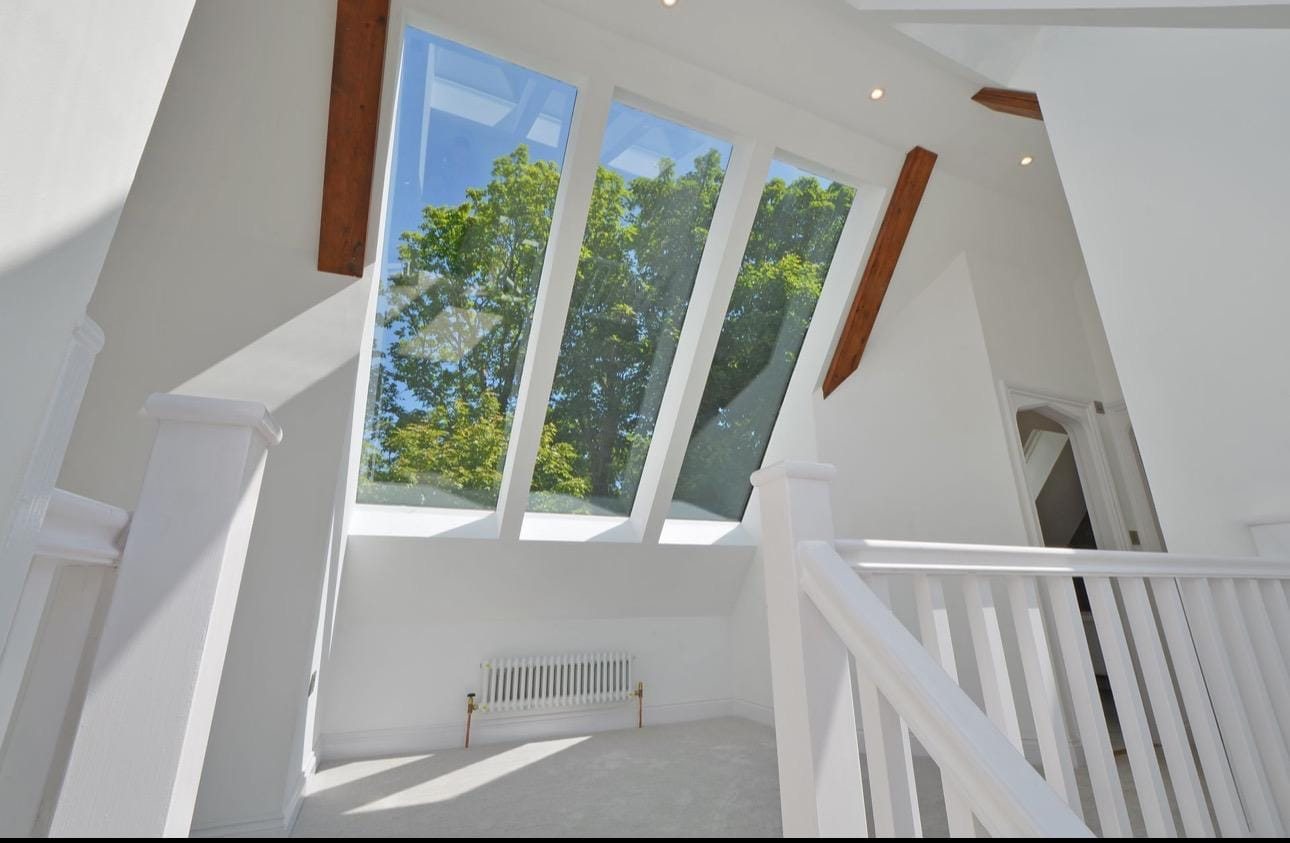 Finished landing with white balustrades and tall glazing in the roof slope
