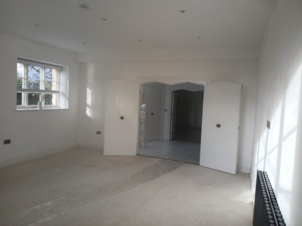 Finished white room with double plank doors open to the hallway