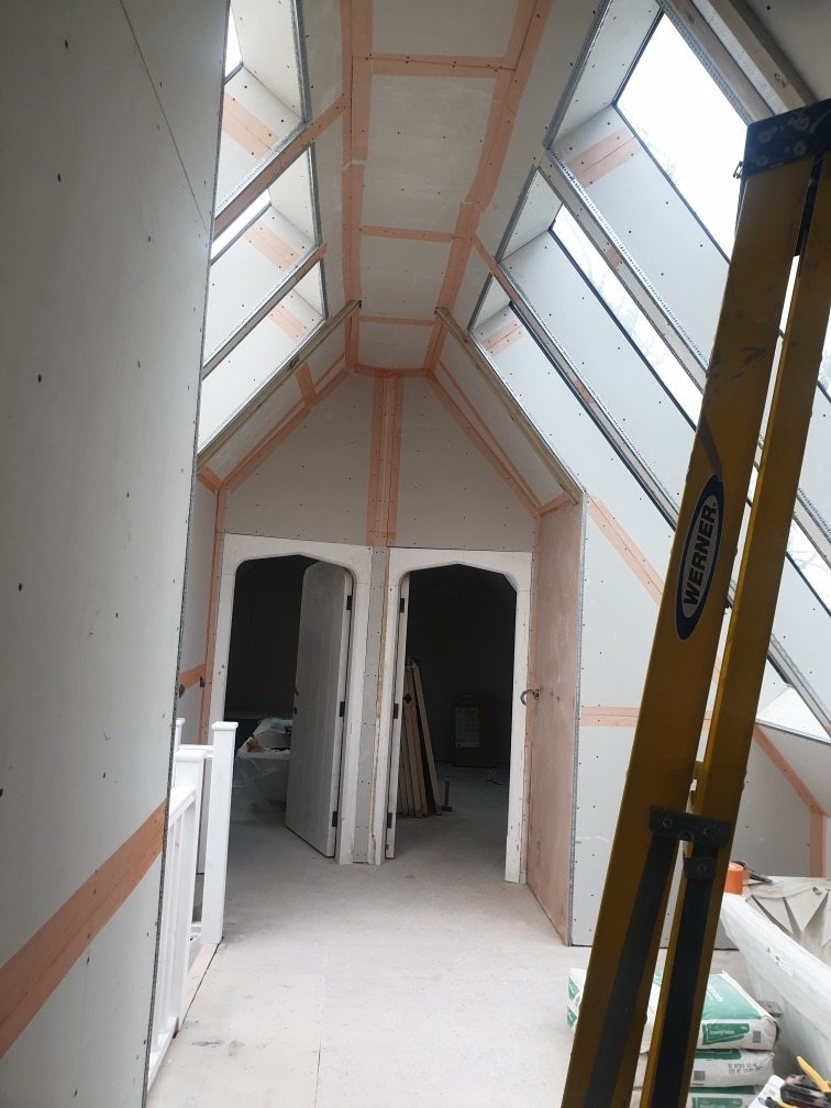 Vaulted room with plasterboard joints taped ready for skimming, under glazed roof panels