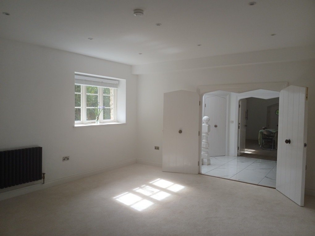 Finished white room with a cottage window and double plank doors opening to a tiled hall