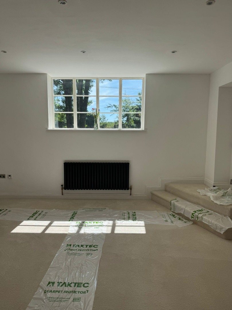 Finished white room with a wide window and a black radiator below it